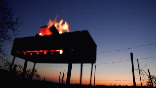 Fire in a bbq, colorful sky after sunset on the background