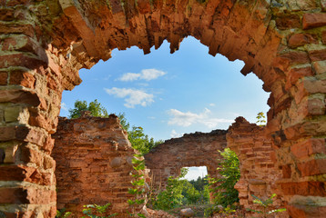 view of the blue sky through the ruined arch of a ruined castle overgrown with grass