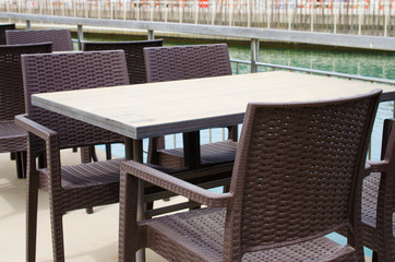 Wicker tables and chairs on the terrace of a cozy summer cafe overlooking the water.
