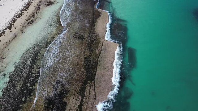 Vertical aerial drone view of tropical coral ocean reef background with turquoise water and tidal waves  in slow motion.