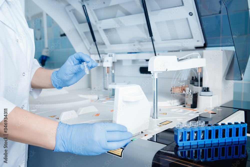 Wall mural laboratory technician sets test sample in automatic express tester