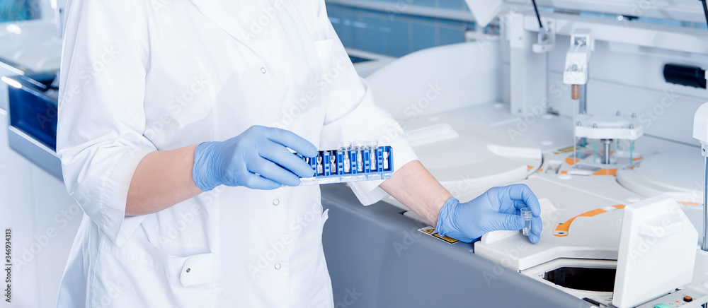 Wall mural laboratory technician sets test sample in automatic express tester