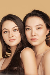 Closeup portrait women with clear skin and natural makeup. Beautiful asian and caucasian girl models background beige. Concept spa care