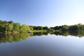 Fototapeta na wymiar Lac de Courcouronnes dans le département 91 en France au printemps. Lac miroir et ciel bleu immaculé.