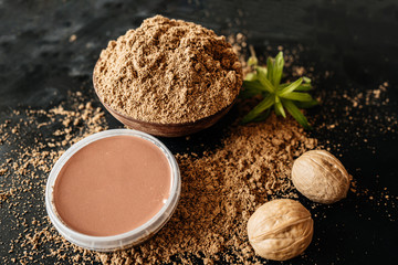 Natural cosmetics for skin care. Walnut placer and green leaf. Body scrub. Natural organic ingredients. Packaging. Empty space for insertion. Home Spa. Black background. Closeup.