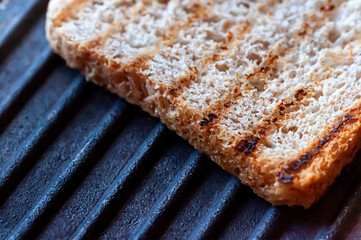 Grilled toast bread with brans on the cast iron pan close up