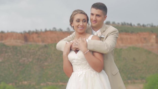 A bride and groom embracing and smiling for their mountain wedding photos