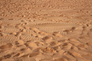 Red sand dunes in Sharjah, UEA during a sunny day. A lot of sand and plenty of footmarks because plenty of tourists have been exploring the dunes. Walking on soft and hot sand offers good exercise