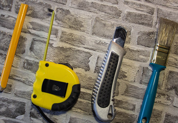 Yellow construction tape measure and yellow pencil on brick background.Brush with a blue pen