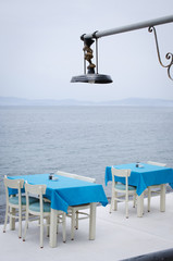 Wicker tables and chairs on the terrace of a cozy summer cafe with sea views.