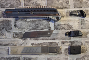 Disassembled stationery knife, blade replacement in knife on a brick wall background.