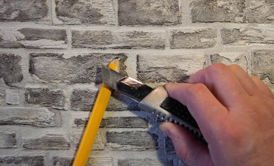 Sharpen a yellow pencil with an office knife Against the background of a brick wall.