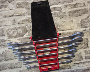 Set of open-end wrenches under the nuts on a brick wall background. .