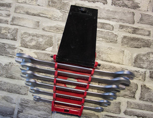 Set of open-end wrenches under the nuts on a brick wall background. .
