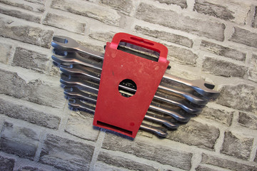 Set of open-end wrenches under the nuts on a brick wall background. .