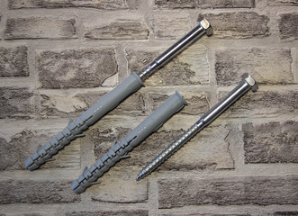 Anchor plug with universal wrench screw against a brick wall.