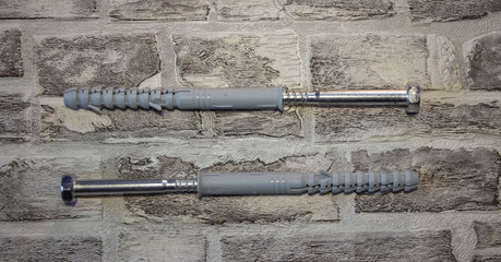 Anchor plug with universal wrench screw against a brick wall.
