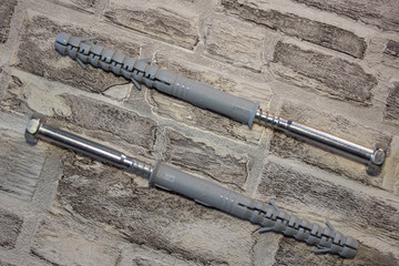 Anchor plug with universal wrench screw against a brick wall.