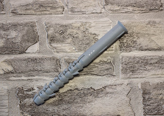 Anchor plug with universal wrench screw against a brick wall.