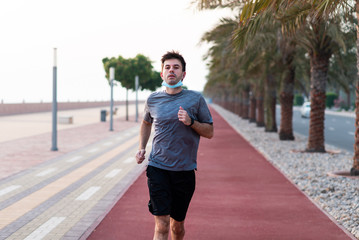 Man jogging on the running track wearing protective mask