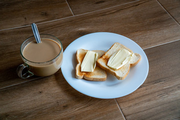 Cup of coffe with milk and two slices of toasted sandwich buttered bread on a white plate. Healthy breakfast with coffee. Side view. Free space for text.