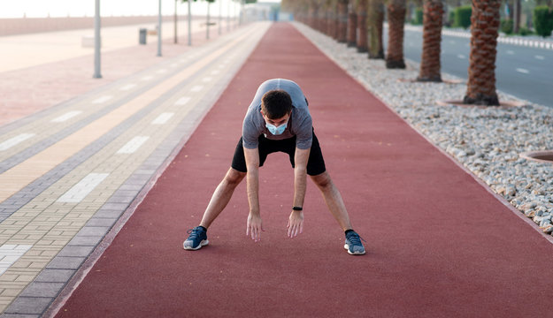 Man exercising outdoors and wearing protective surgical mask