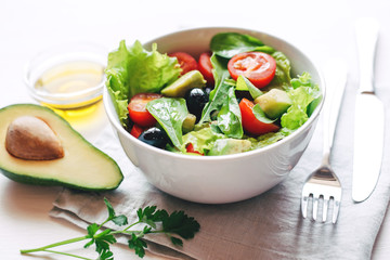 Fresh salad of avocado, cherry, arugula and olives made at home. Vegan food. The concept of healthy eating. Front view.