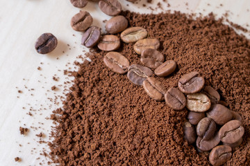 Top view of coffee beans and ground coffee on wooden background, roasted coffee volcano like anthill