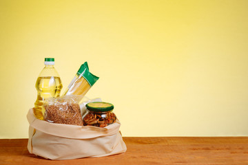 Different Food In Paper Bag on Wooden Table, on Yellow Background. Grocery Shopping Concept