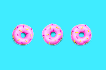 Three pink donuts from plasticine on bright light blue background. Minimal summer concept. Banner for national donut day and holidays.