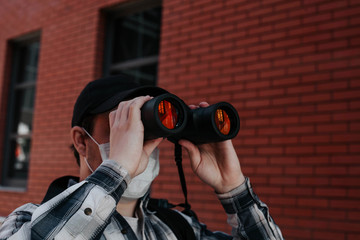 the masked man looks through binoculars