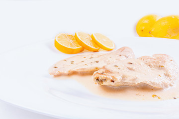 chicken fillets in cream sauce with lemon and spices, on a white background.