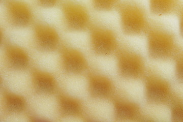 Close up of repeated geometric square pattern of yellow foam from a top down angle. Texture, pattern, background
