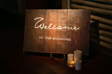Wooden table board sign at the wedding on the beach with welcoming romantic words