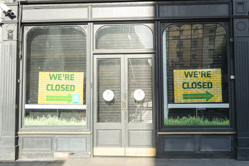 Shopfront closed during daytime in the city, with shutters down and closed sign in windows