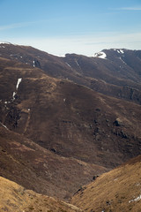 Distant mountains covered by snow and dark, burnt trees and ground, recovering from a fire last summer