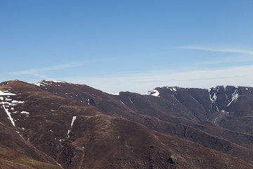 Distant mountains covered by snow and dark, burnt trees and ground, recovering from a fire last summer