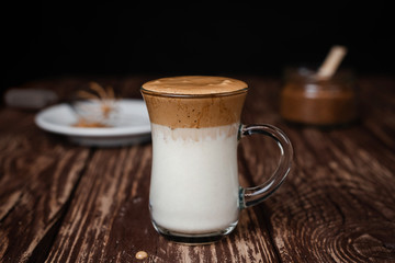 Iced Dalgona Coffee, a trendy fluffy creamy whipped coffee on a wooden table. Levitating the spoon with the foam. Close-up, vertical view.