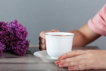 woman drink coffee and lilac on table