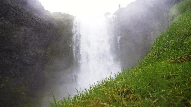 Green grass and the Dynjandi waterfall, overcast day, in West fjords, Iceland - Handheld, slow motion shot