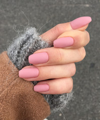 Woman's hand with freshly made pink manicure. Powder light pink nails, mohair wool sweater, grey...