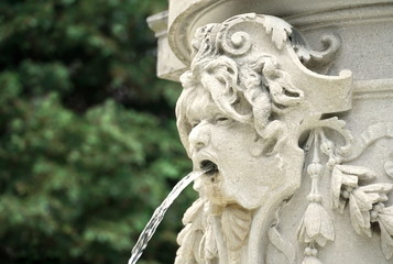 Fototapeta na wymiar Fountain with water. Detail of the street fountain, the head of a mythological being with water in mouth