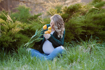 A shot of a young beautiful woman in her third trimester of pregnancy outdoors with a bouquet of...