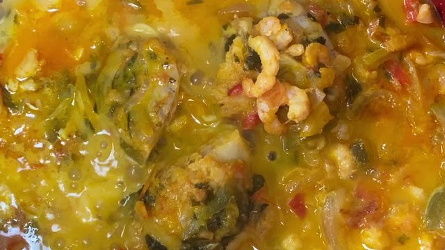 Cooking a moqueca dish. Brazilian traditional food made with fish and shrimp, coconut milk and azeite de dende.