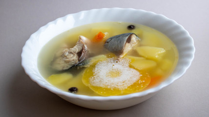 Delicious hot fish soup from sea fish in a white plate on a gray table