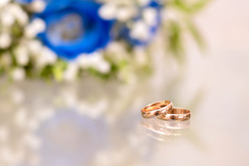 Gold wedding rings next to the bride's bouquet