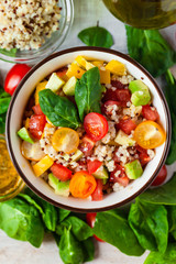 Concept of healthy food, clean eating, low calories delicious meal. Salad with quinoa and fresh vegetables with olive oil in blue bowl. Light tasty lunch. Close up wooden background top view flat lay