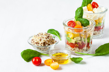 Concept of healthy food, clean eating, low calories delicious meal. Salad with quinoa and fresh vegetables with olive oil in glass jar.  Zero waste no plastic. Close up white background copy space