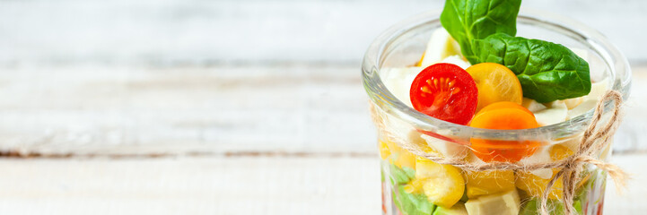 Concept of healthy food, clean eating, low calories delicious meal. Salad with quinoa and fresh vegetables with olive oil in glass jar.  Zero waste. Close up wooden background. Banner, copy space
