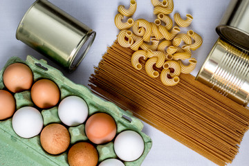 Fototapeta na wymiar eggs in a box, canned food, macaroni, spaghetti on a gray background form a grocery basket, essential food,